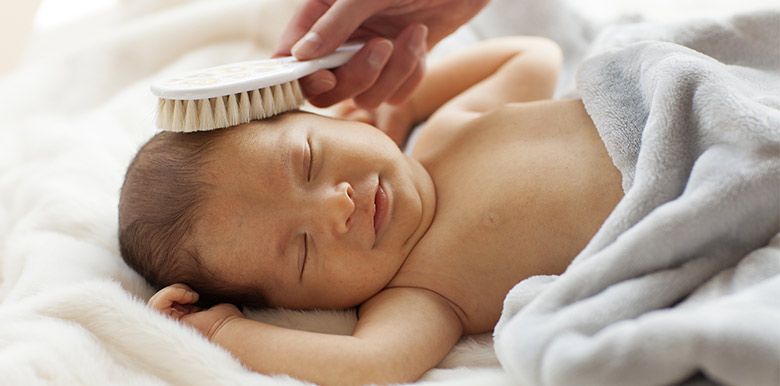 bébé se faisant coiffer avec une brosse à cheveux 